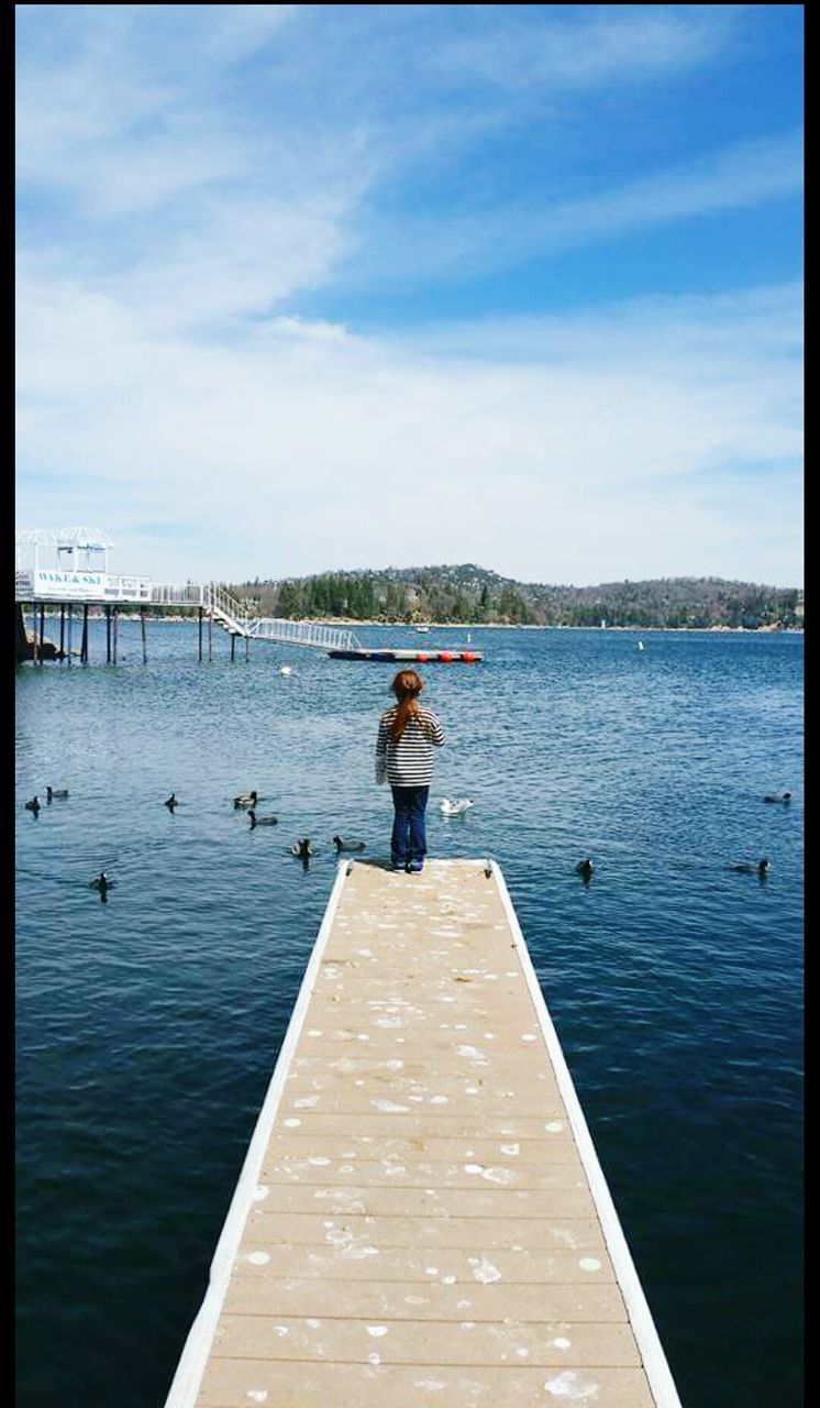 water, real people, day, nature, one person, sky, leisure activity, outdoors, full length, beauty in nature, men, lake, scenics, standing, sunlight, lifestyles, vacations, women, nautical vessel, tree, young adult, people