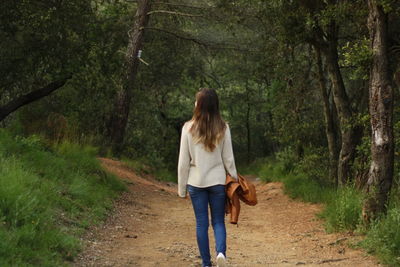 Rear view of man walking on footpath in forest