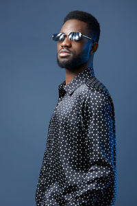 Young man standing against blue background