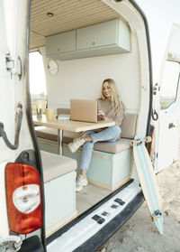 Smiling young freelancer working on laptop sitting inside motor home