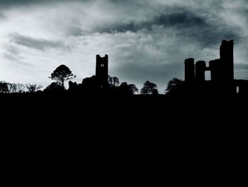 Low angle view of silhouette trees against cloudy sky