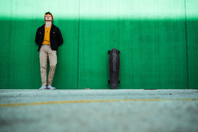 Full length of teenage boy standing against wall