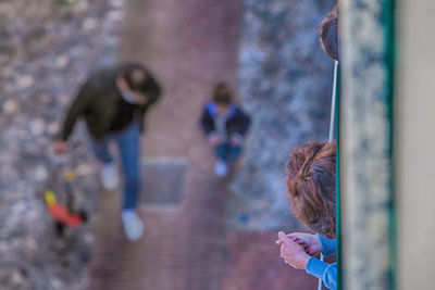 High angle view of woman watching and man and girl walking on street