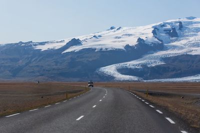 Road amidst snowcapped mountains against sky