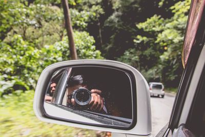 Reflection of digital camera in side-view mirror of car