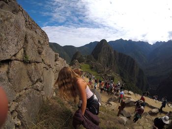 Rear view of people standing on rock against sky