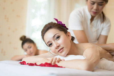 Midsection of masseur massaging young woman on table in spa