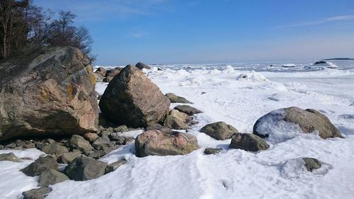 Rocks on beach against sky during winter