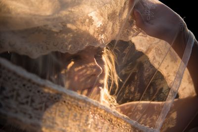 Close-up of bride wearing veil looking away while standing outdoors during sunset