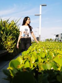 Woman standing by flowers against sky