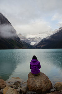 Rear view of man looking at lake against sky