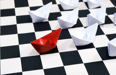 High angle view of paper boat on chess board