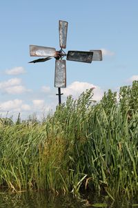 Low angle view of cross on field against sky