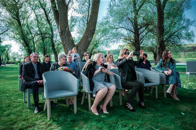 Group of people on grassland against trees