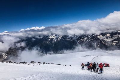 People on snowcapped mountains against sky during winter