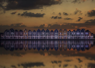 Houses by sea against sky during sunset