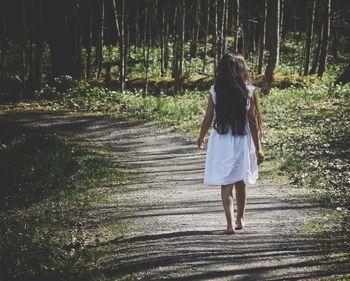 Rear view of girl walking on footpath in forest