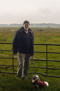 Man with his dog in front of a pasture