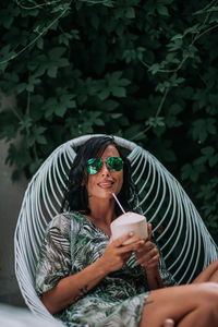 Portrait of young woman holding sunglasses