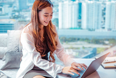 Young woman looking away while sitting on mobile phone