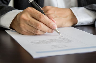 Midsection of businessman signing document at desk