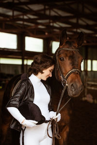 Cute girl jockey, next to beautiful brown horse shooting close-up. beautiful