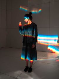 Full length of young woman standing on tiled floor with lights