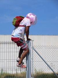 Full length of girl standing by fence against sky