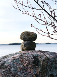 Stack of stones on rock by sea against sky