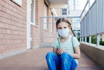 Portrait of girl wearing mask sitting outdoors