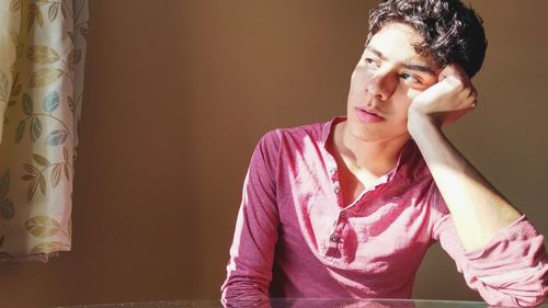 Portrait of young man sitting against wall