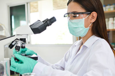 Female scientist using microscope in laboratory