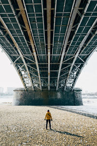 Rear view of a man walking under bridge