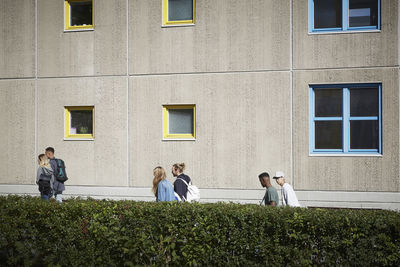 University students walking by hedge in campus on sunny day