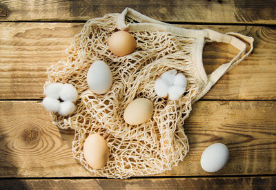 Easter concept. beige mesh shopping bag with brown chicken eggs on a wooden background.