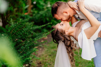 Side view of woman with baby standing against plants