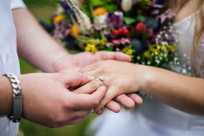 Midsection of man putting ring in woman finger outdoors