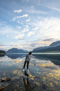 Side view of man standing by lake against sky