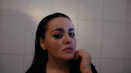 Portrait of young woman against wall at home