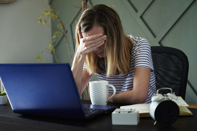 Exhausted woman at home office workplace using laptop