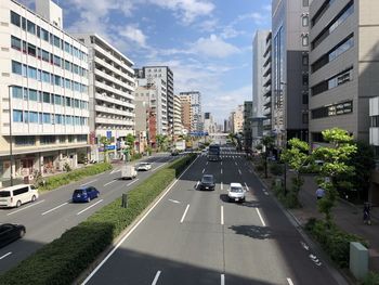 Traffic on road amidst buildings in city against sky