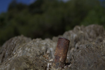 Close-up of old metallic pipe amidst rock