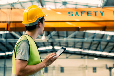 Young man using mobile phone while standing on laptop