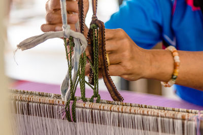 Midsection of man weaving loom in workshop