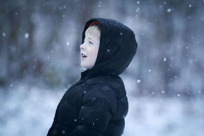 Close-up of boy in warm clothing standing outdoors during snowfall