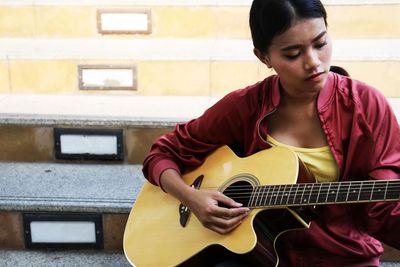 Full length of man playing guitar against wall