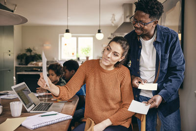 Multiracial couple discussing over financial bill at home