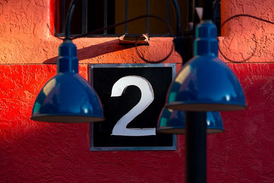 Close-up of lamp post against number 2 on red wall