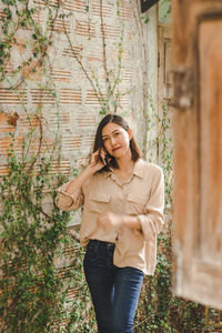 Portrait of beautiful young woman standing against tree