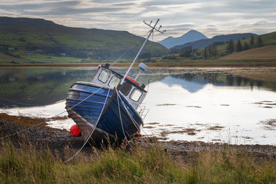 Old boat abandoned and moored on a loch coastline in scotland. concept of sadness and loneliness